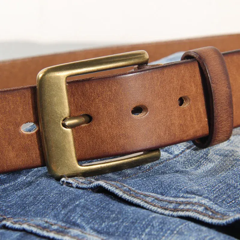 Leather belt with brass buckle on denim jeans. Classic solid brass and full-grain leather belt for a timeless, durable accessory.