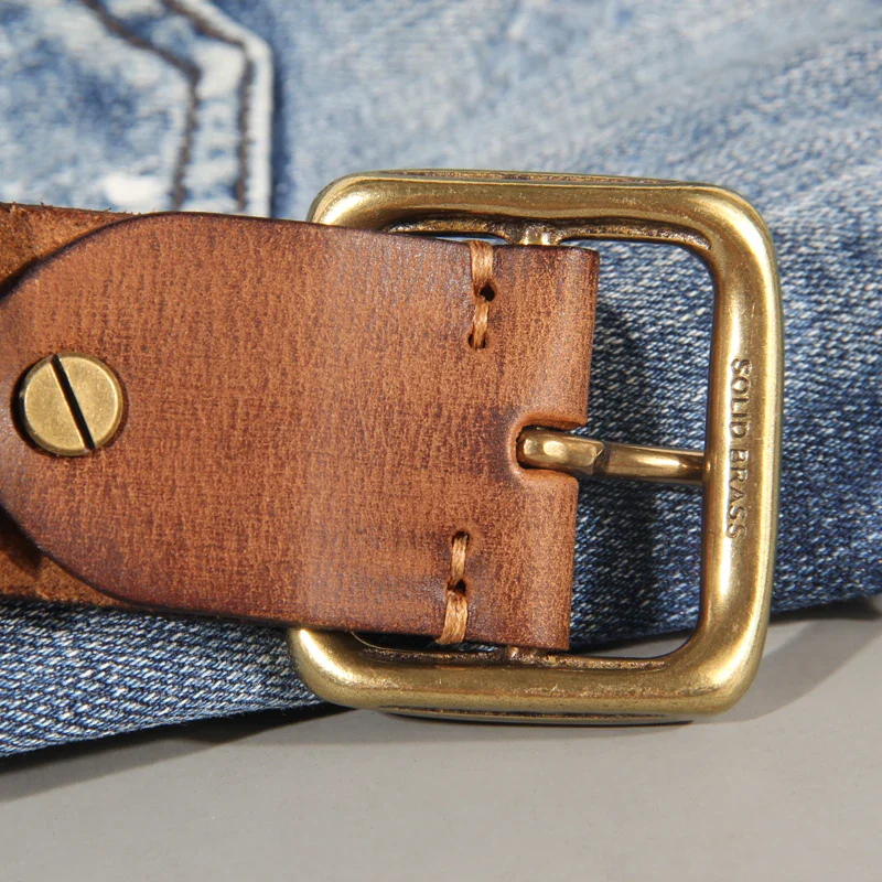 Leather Belt with Brass Buckle Close-up of a full-grain leather belt with solid brass buckle on denim jeans.