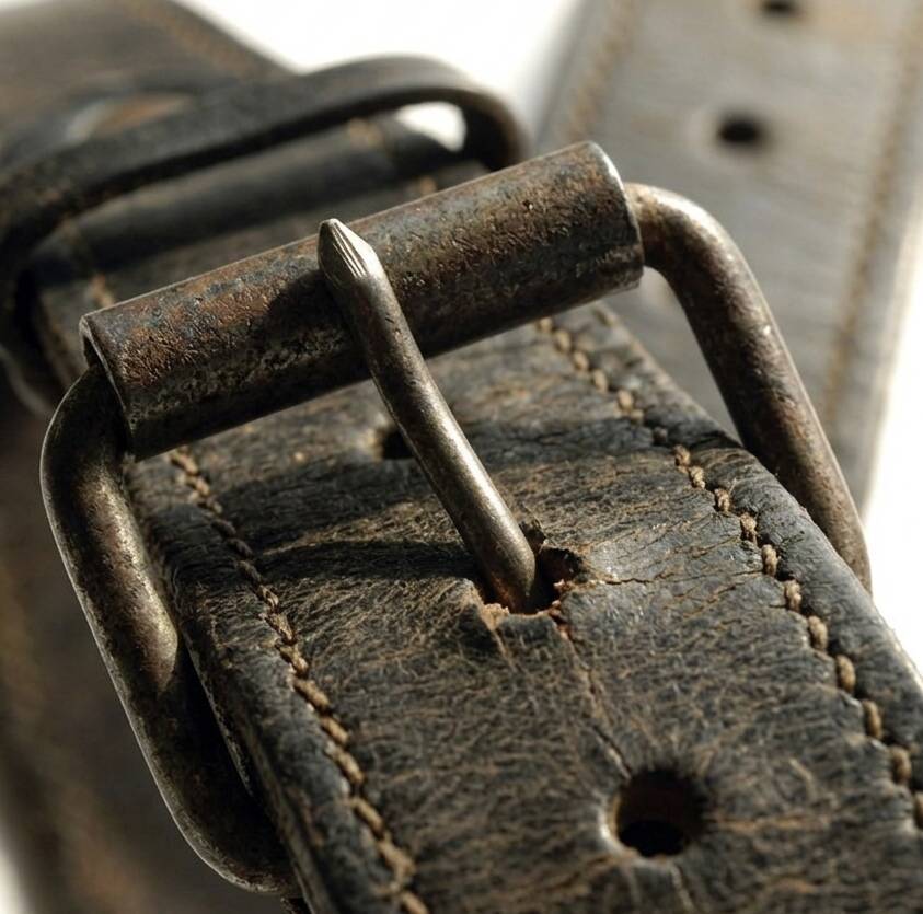 Close-up of a rusted pin buckle on a leather belt.