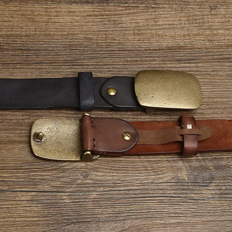 Vintage Brass & Cowhide Belts – The Iron Range Two vintage brass and cowhide belts with brass buckles on wooden surface.