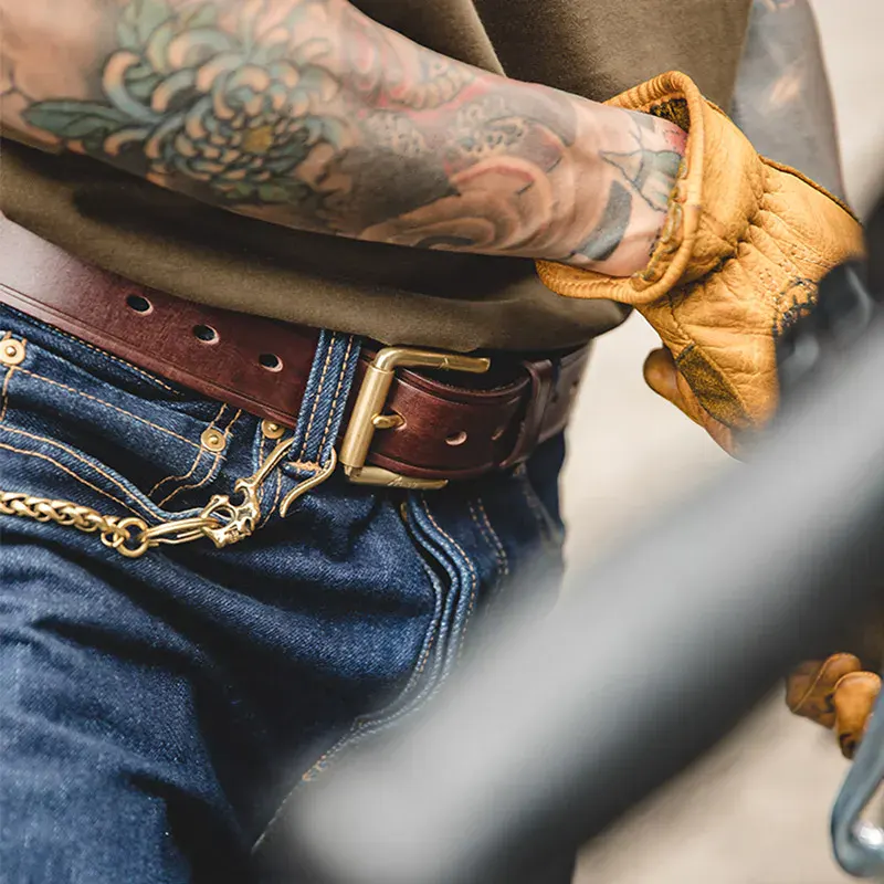Leather men’s belt with pin buckle and tattooed arm, casual fashion accessory. Genuine leather men's belt featuring a stylish pin buckle, perfect for casual and formal outfits.