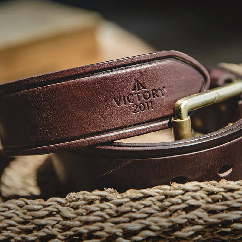 Leather men’s belt with engraved “VICTORY 2011” and brass buckle, stylish and high-quality accessory. High-quality men's leather belt with engraved